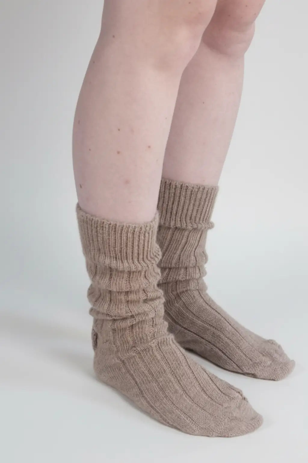 half british alpaca lounge socks in brown, worn slightly slouched to show the ribbed knit texture and natural alpaca fibre softness against a white background.