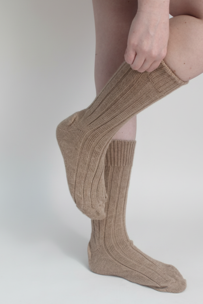 half british alpaca lounge socks in brown, worn and gently adjusted to highlight the ribbed knit texture and soft alpaca fibre against a neutral background