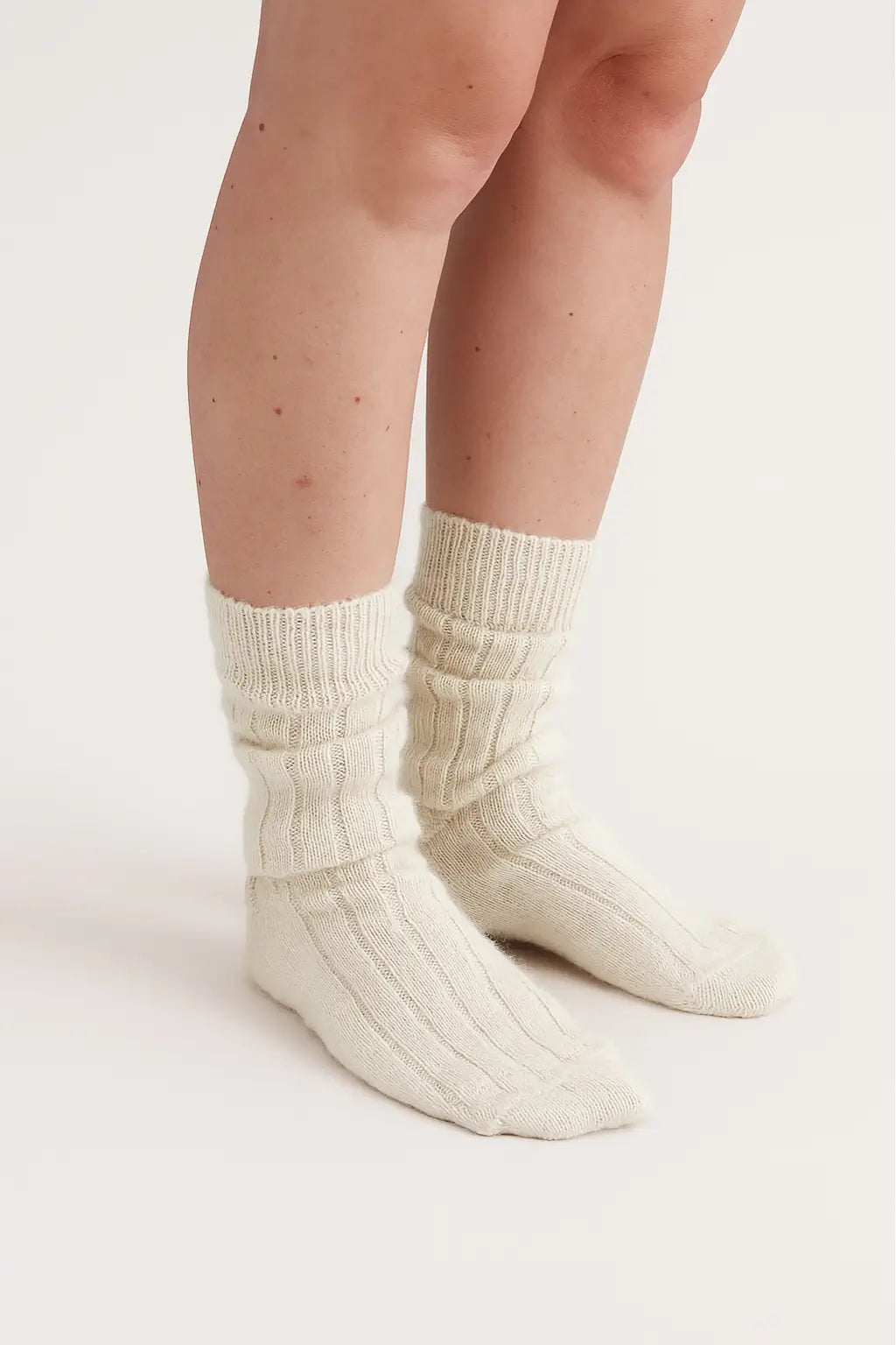half british alpaca lounge socks in cream, worn and softly scrunched to highlight the ribbed knit texture and plush alpaca fibre against a light background