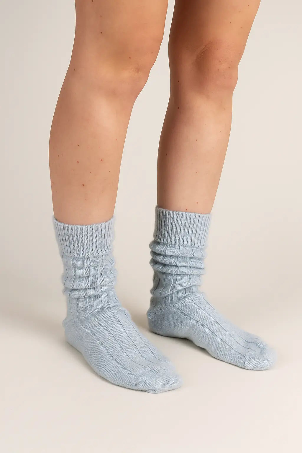 half british alpaca lounge socks in light blue, worn and softly scrunched to show the ribbed knit and plush alpaca texture against a neutral background