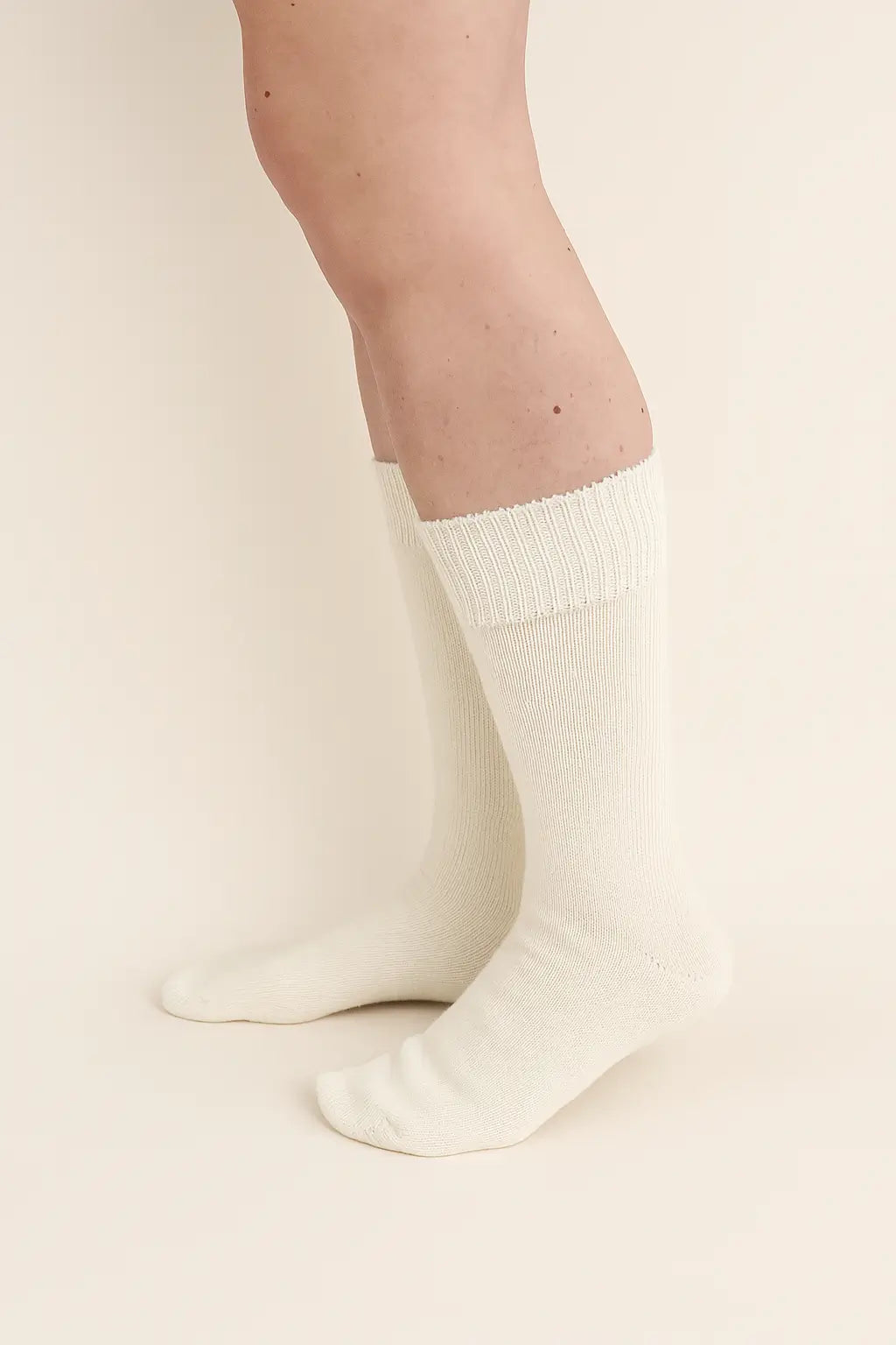 half british everyday alpaca socks in ivory, worn to show the soft alpaca wool texture and refined ribbed design against a neutral beige background
