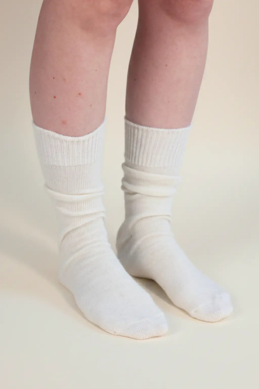 half british everyday alpaca socks in cream, worn and gently scrunched on a beige background to highlight the softness and ribbed alpaca wool texture